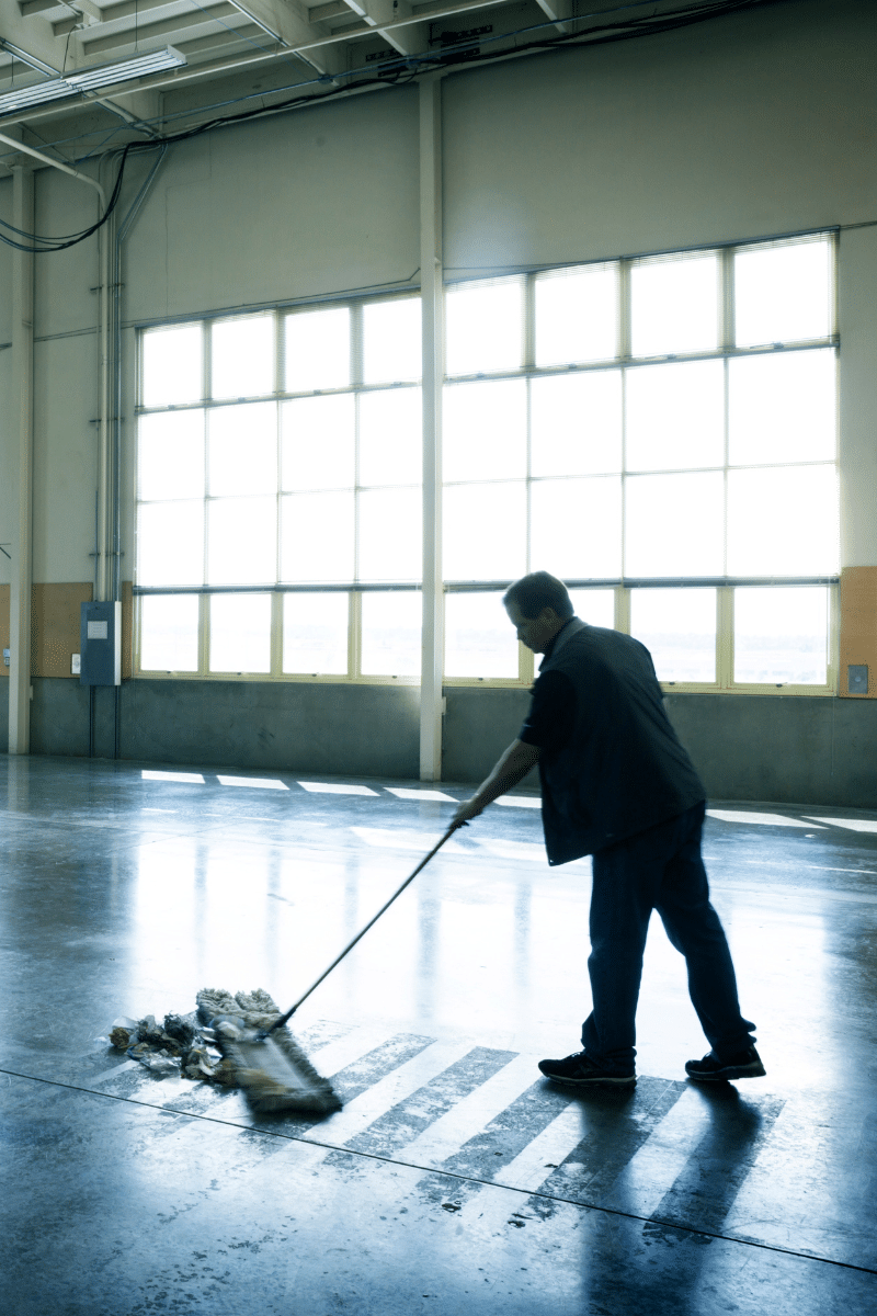 un homme qui nettoie à la serpillère un hangar commercial