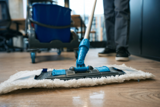 un employée en train de passer la serpière dans un hall d'entrée